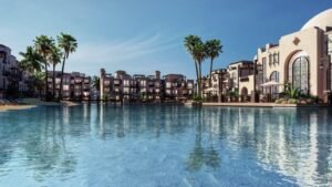 CALA Sahl Hasheesh residential buildings with traditional architecture overlooking a large lagoon and palm trees under clear sky